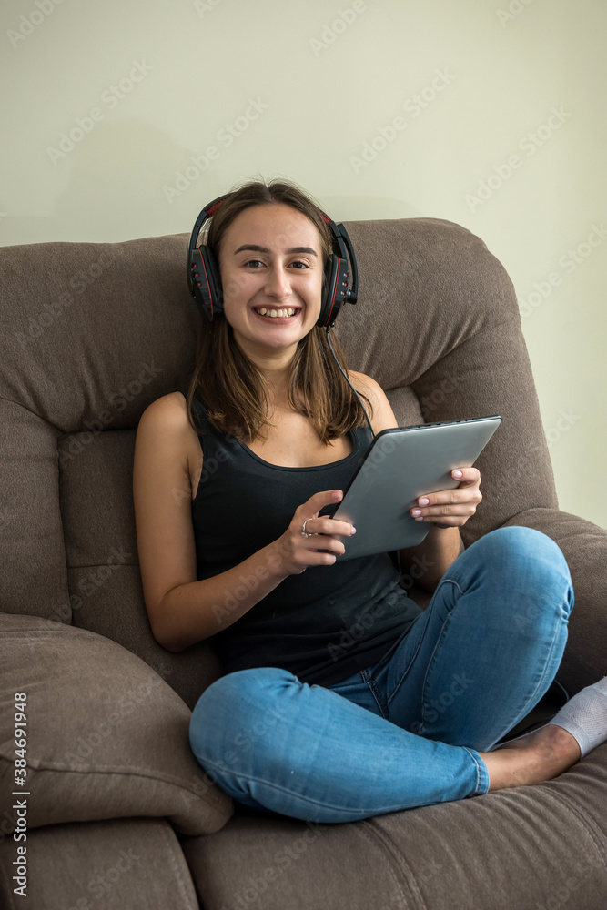 Obraz premium Young pretty slim woman looking at her tablet lying on the comfy couch