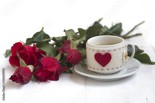 coffee cup with a red heart and a bouquet of red roses on a white background. a gift for your beloved. 