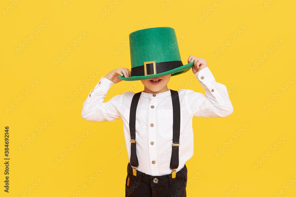 Smiling little child boy in green leprechaun hat on yellow background. St. Patrick Day celebration. Funny face Smiling little child boy in green leprechaun hat on yellow background. St. Patrick Day celebration. Funny face