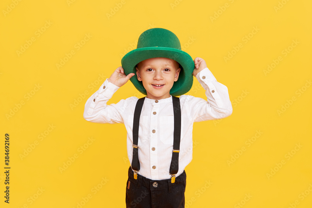 Smiling little child boy in green leprechaun hat on yellow background. St. Patrick Day celebration. Funny face Smiling little child boy in green leprechaun hat on yellow background. St. Patrick Day celebration. Funny face