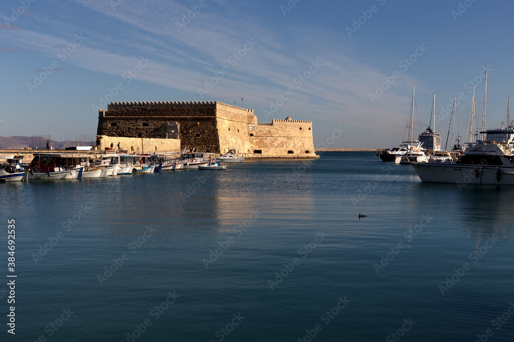 Ancient, urban, medieval, marine, Venetian fortress Kules (island Crete, city Heraklion, Greece) and fishing boats on a sunny morning.