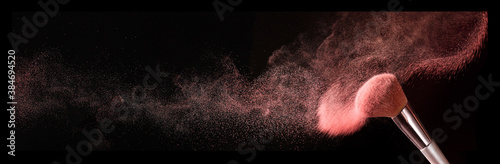 Makeup brush and burst of cosmetics on dark background © Pixel-Shot