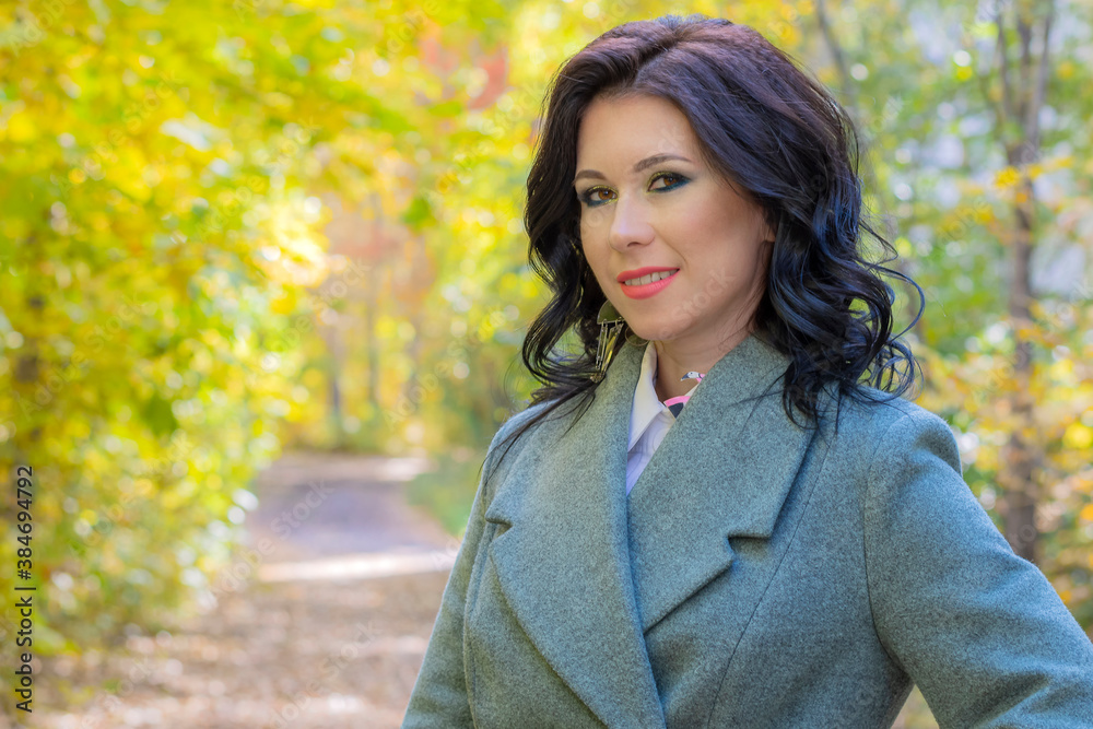 Happy brunette girl stands on a background of yellow autumn foliage in the park Happy brunette girl stands on a background of yellow autumn foliage in the park