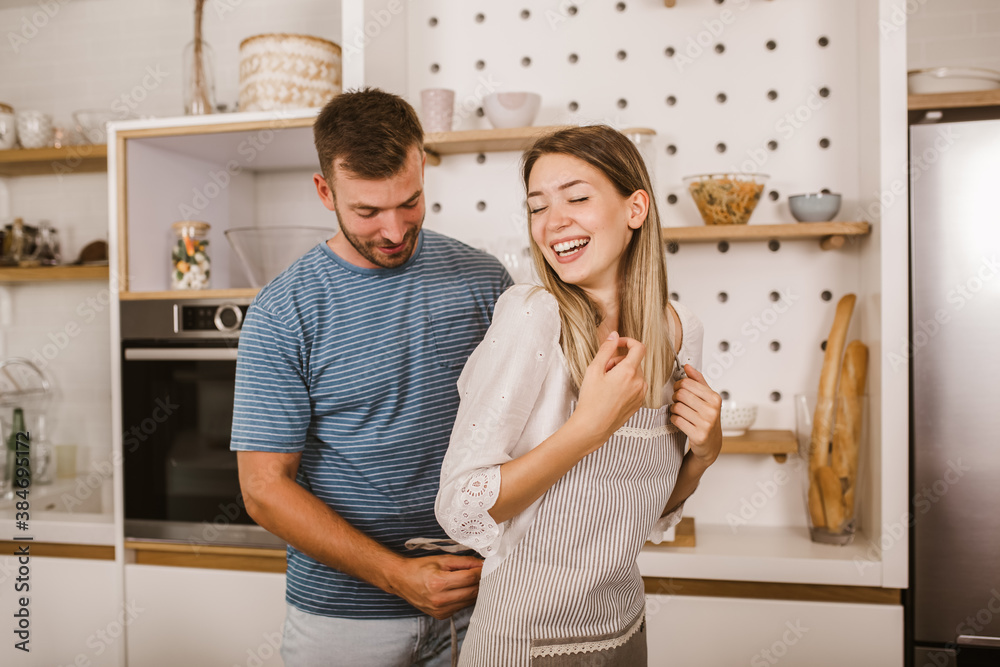 Young beautiful couple in kitchen having fun.