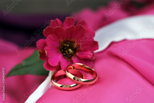 Golden wedding rings and pink flower, romantic image