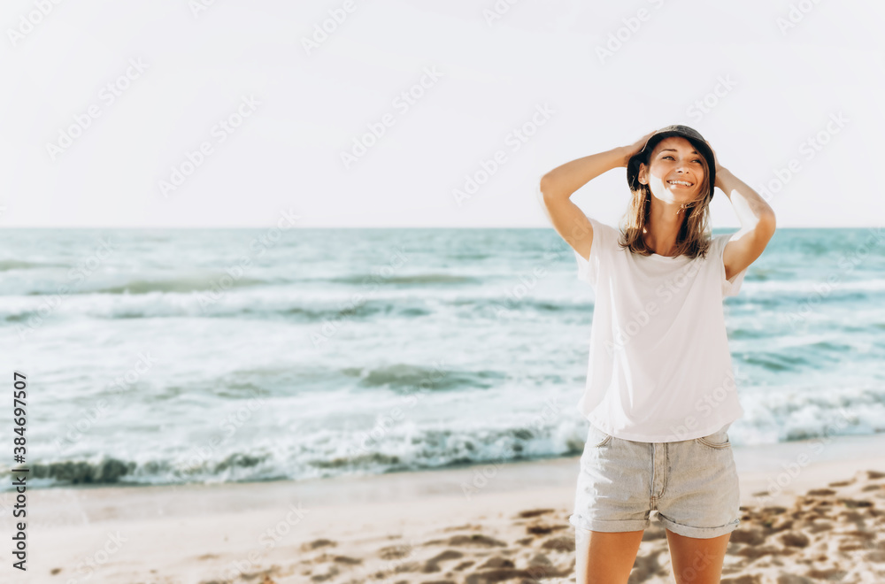 Portrait of happy beautiful young woman standing on the beach at sunset. Positive mood, summer vacation, sunny concept Portrait of happy beautiful young woman standing on the beach at sunset. Positive mood, summer vacation, sunny concept