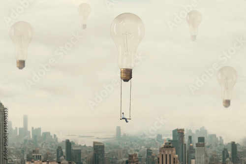 surreal moment of a woman traveling on a swing carried by a light bulb over a metropolis photo