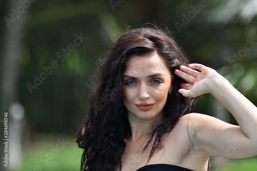 Natural cosmetics. Sensual woman against tropical leaves, looking at camera