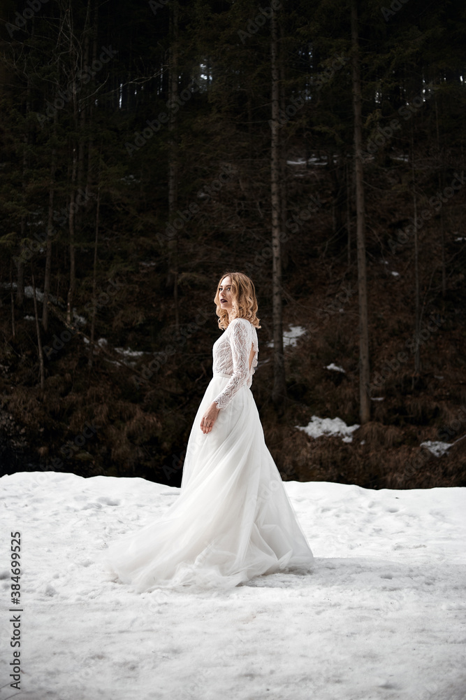 blonde bride in snow park at winter wears minimalist white wedding dress blonde bride in snow park at winter wears minimalist white wedding dress