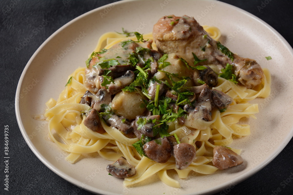 Fricassee - French Cuisine. Chicken stewed in a creamy sauce with mushrooms in a white plate on a black table Fricassee - French Cuisine. Chicken stewed in a creamy sauce with mushrooms in a white plate on a black table