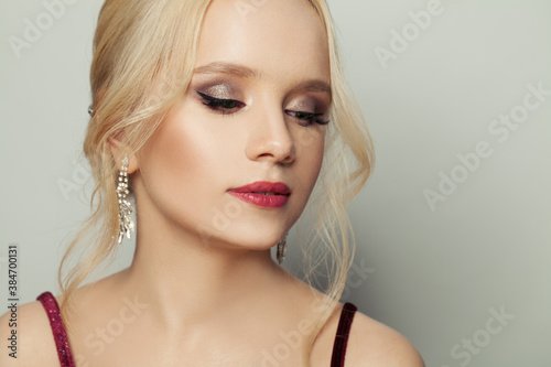 Beautiful young woman with blonde hair and makeup on white background