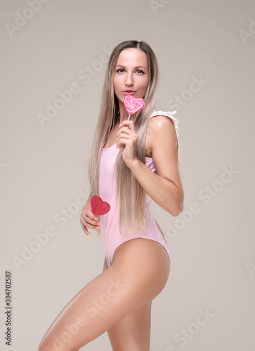 Beautiful slim and fit girl with long blond hair in pink swimsuit. Glowing skin