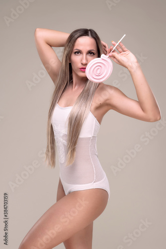 Beautiful slim and fit girl with long blond hair in pink swimsuit. Glowing skin