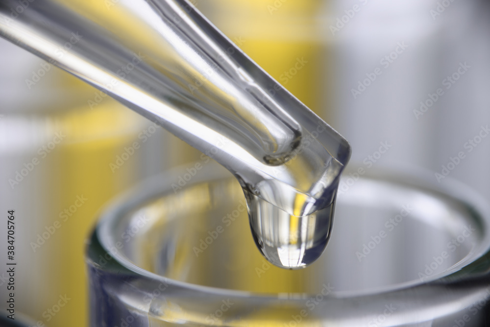 Chemical pipette dispenser drips yellow liquid into glassware closeup. Pharmaceutical industry concept. Chemical pipette dispenser drips yellow liquid into glassware closeup. Pharmaceutical industry concept.