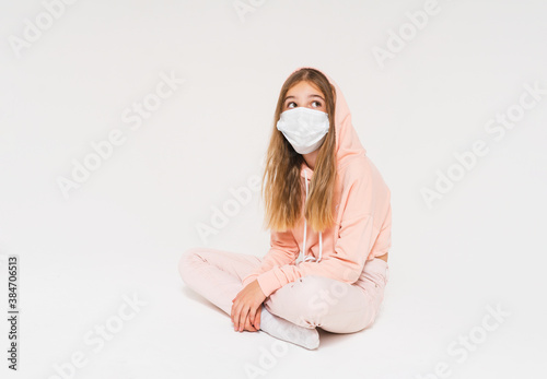 Sad teen girl in pink hoodie in face mask girl in closed position isolated on the white background