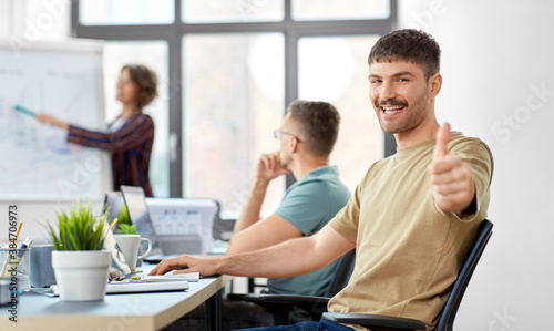 business and people concept - happy smiling man showing thumbs up at office conference