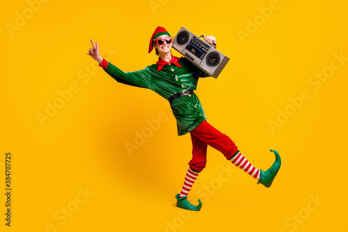 Full length body size view of his he nice attractive skinny cheerful cheery funny teenage guy elf carrying tape player dancing isolated over bright vivid shine vibrant yellow color background photo