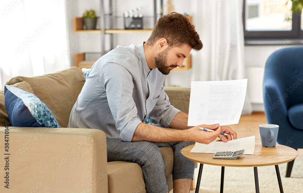 business, finances, accounting and people concept - man with calculator counting and filling papers at home business, finances, accounting and people concept - man with calculator counting and filling papers at home