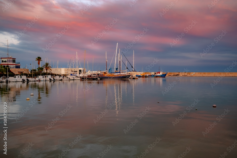
Boats in the port of Benicarló at sunset red in autumn