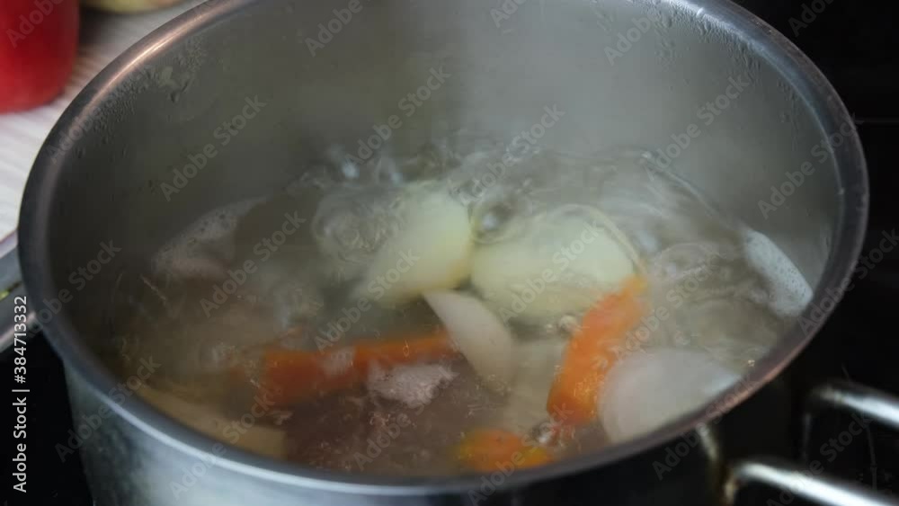 Chicken soup with vegetables boiling in a pot close-up. Home diet food concept Chicken soup with vegetables boiling in a pot close-up. Home diet food concept