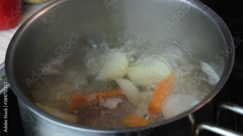 Chicken soup with vegetables boiling in a pot close-up. Home diet food concept