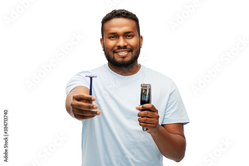 shaving, grooming and people concept - smiling young african american man choosing between manual razor blade and trimmer over white background