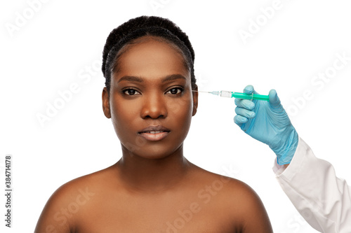 beauty, plastic surgery and people concept - portrait of beautiful young african american woman and hand in medical glove with syringe over white background