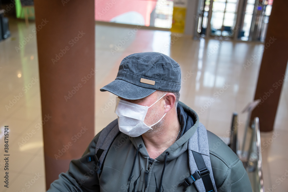 One middle-aged 40-45 European man wearing a properly worn white medical mask in a public place in a shopping center during the coronavirus epidemic, protecting against the Covid-19 pandemic One middle-aged 40-45 European man wearing a properly worn white medical mask in a public place in a shopping center during the coronavirus epidemic, protecting against the Covid-19 pandemic