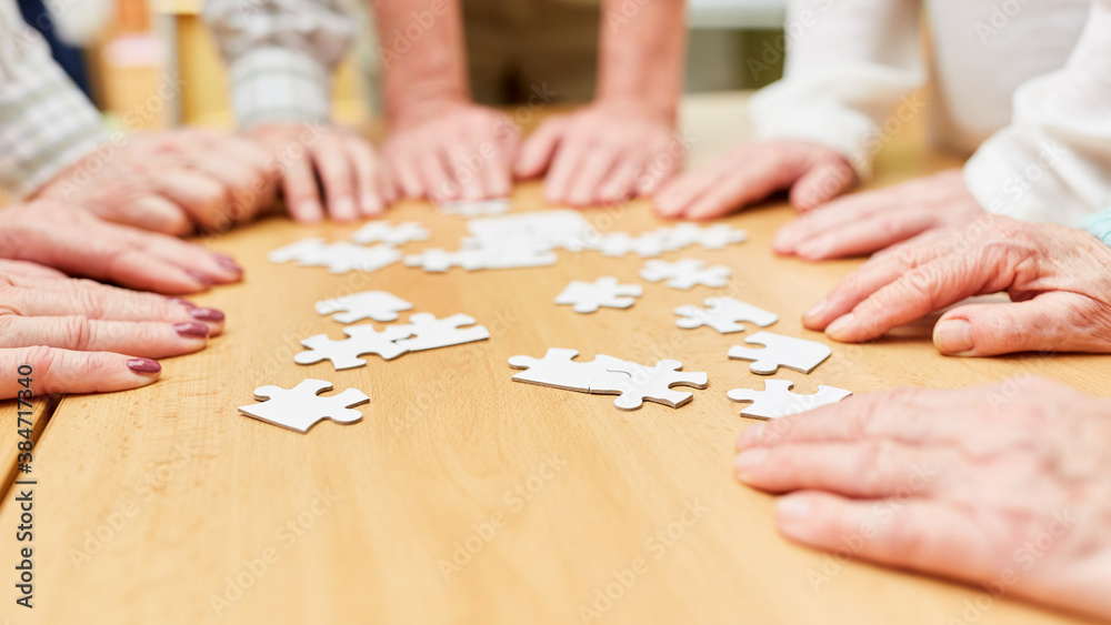 Hände von dementen Senioren beim Puzzle spielen auf dem Tisch im Altenheim