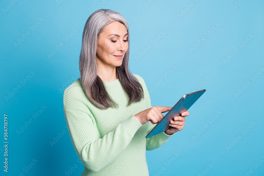 Photo of old attractive focused lady use tablet isolated over blue pastel color background Photo of old attractive focused lady use tablet isolated over blue pastel color background