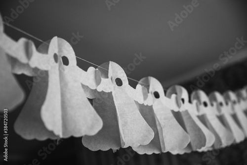 Halloween decorarion. Concept DIY and children creativity. Step-by-step instructions: making garland of ghosts from white and black paper. Step 3 child throughout rope from paper ghost
