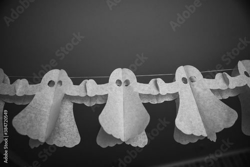 Halloween decorarion. Concept DIY and children creativity. Step-by-step instructions: making garland of ghosts from white and black paper. Step 3 child throughout rope from paper ghost photo