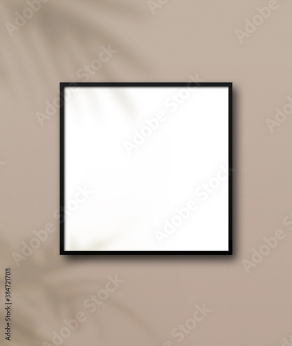 Black square picture frame hanging on a light beige wall