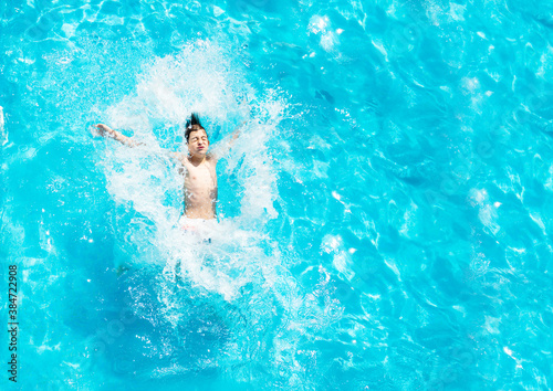 Portrait of a Boy falls into the pool water backwards splashes view from above