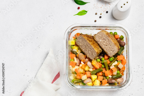 Pork patties, cut in half, steamed vegetables in glass container. Copy space.