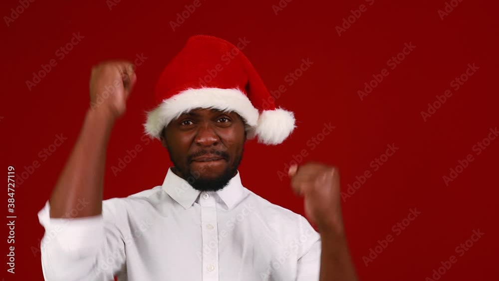 brazilian man wear santa claus headwear isolated over red color background dancing