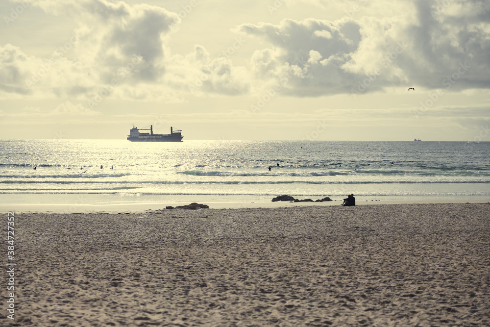Sandy beach with container ship silhouette in the sea horizon