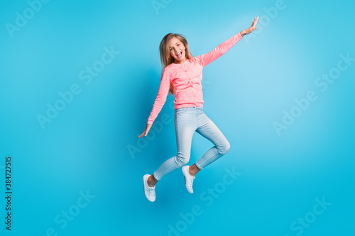 Photo portrait of girl jumping up making plane with hands isolated on pastel blue colored background