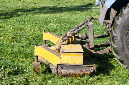 close up of tractor mows grass on lawn in city yard