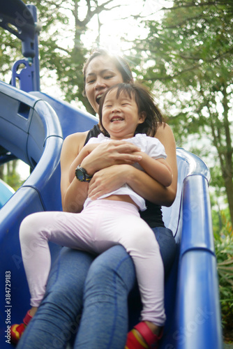 Asian Chinese Mother and Child sliding down a slide having fun © 1000words