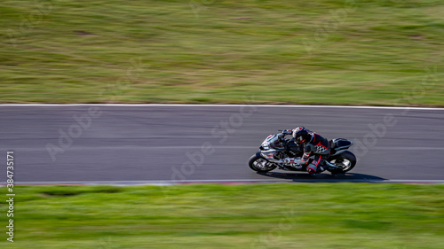 A panning shot of a racing bike cornering as it circuits a track.