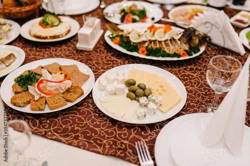 The holiday table cheese, meat, salads. Served table with food. Festive table. Table at restaurant before starting to celebrate.