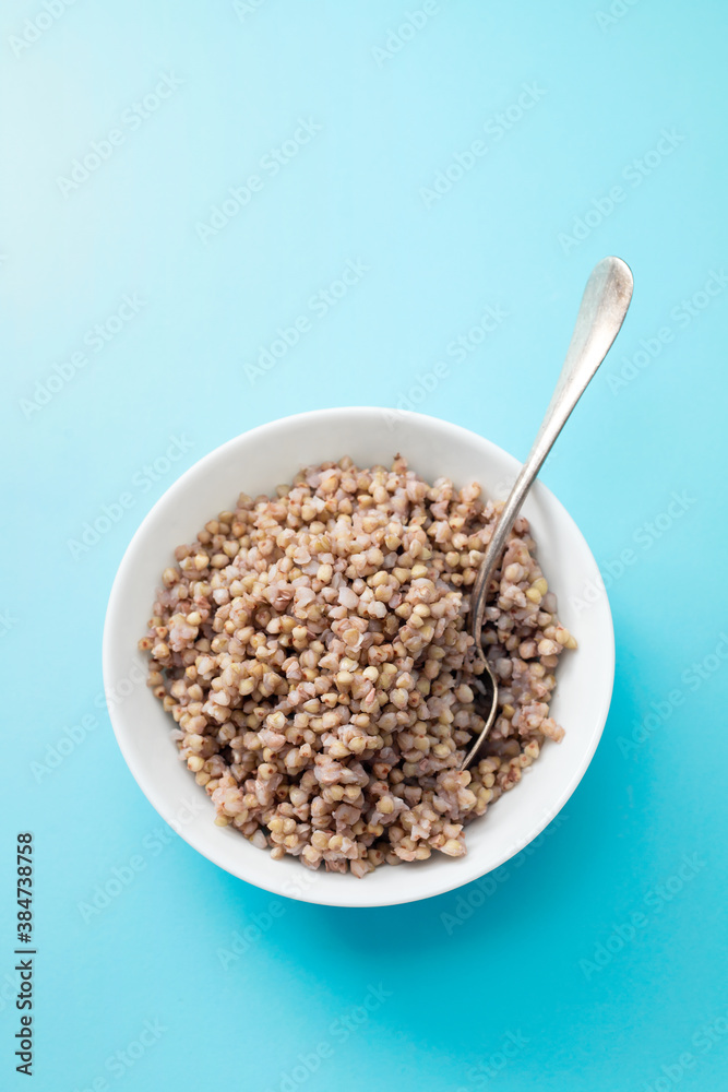 boiled buchwheat in white bowl on blue background boiled buchwheat in white bowl on blue background