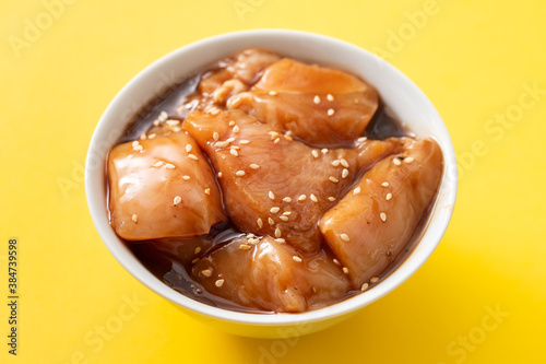 raw chicken with sauce and sesame in white bowl
