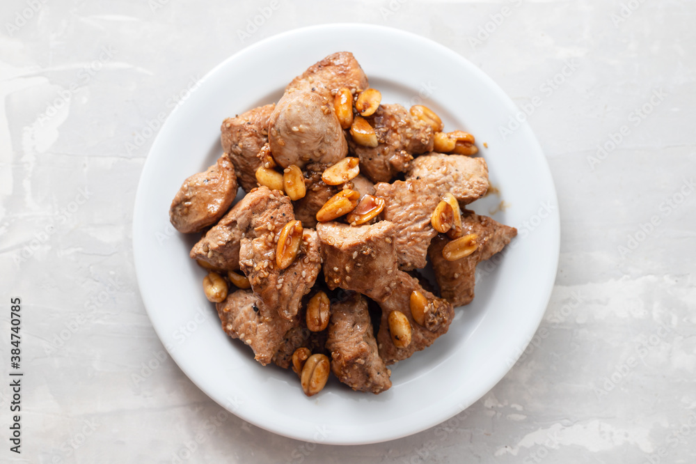 meat with nuts on white plate on ceramic background meat with nuts on white plate on ceramic background