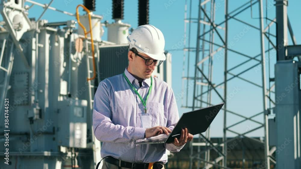 Energetics specialist with a laptop is checking a power station. Energy efficiency, energy saving concept.