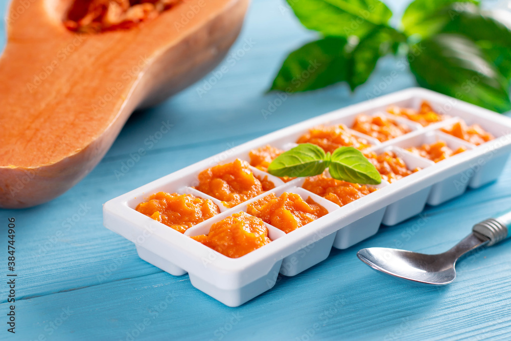 Pureed baby food in ice cube trays ready for freezing on blue wooden table. Baby food. Pureed baby food in ice cube trays ready for freezing on blue wooden table. Baby food.