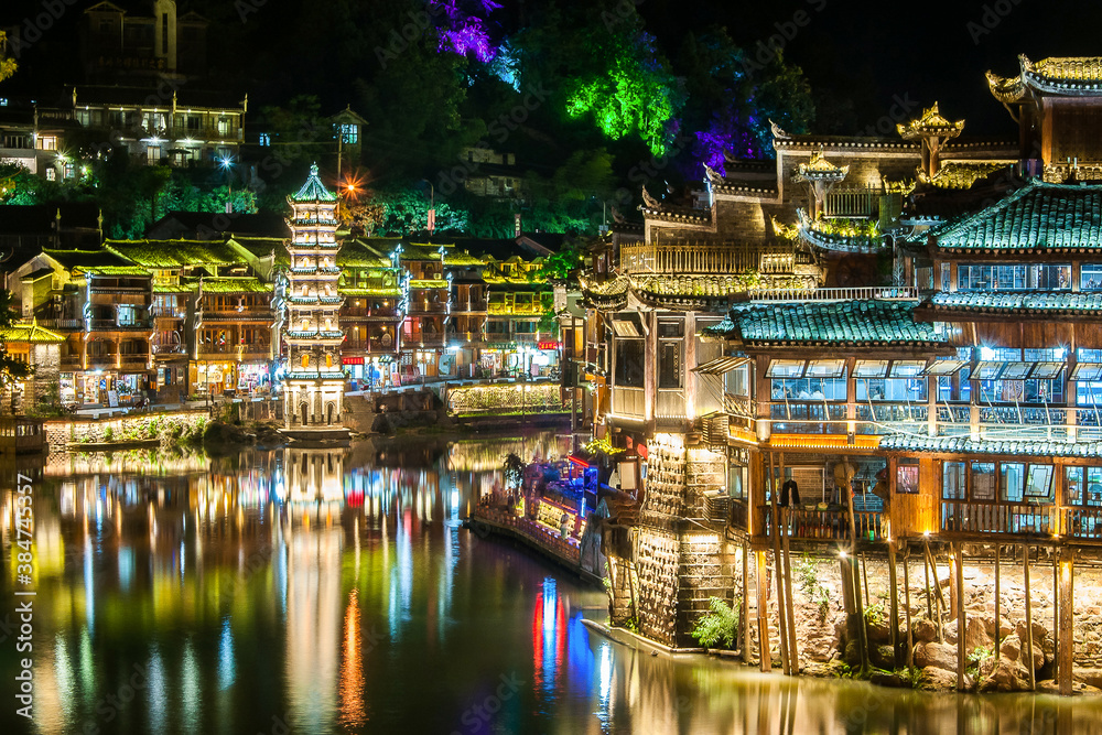 Beautiful night scenery of Fenghuang (Phoenix) ancient town, Hunan province, China. Cityscape at night with reflection light in the river.