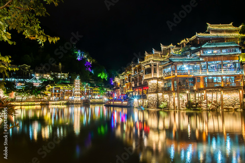 Beautiful night scenery of Fenghuang (Phoenix) ancient town, Hunan province, China. Cityscape at night with reflection light in the river.