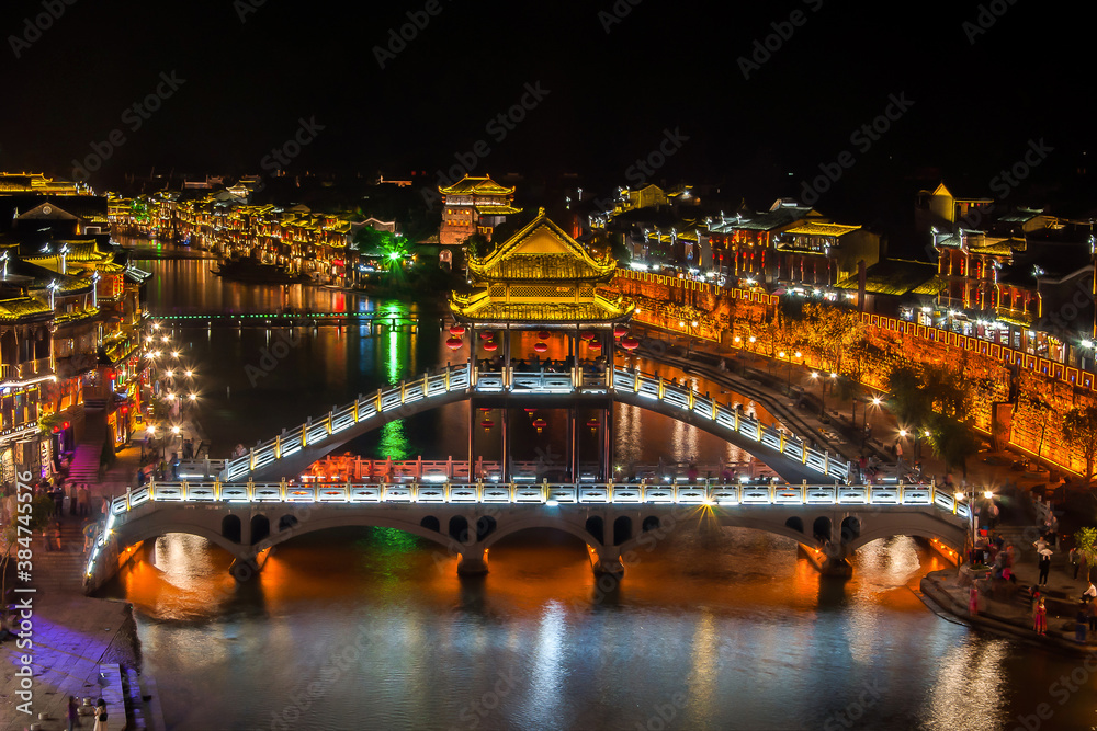 Beautiful night scenery and Fenghuang Bridge of Fenghuang (Phoenix) ancient town, Hunan province, China. Cityscape at night with reflection light in the river. Beautiful night scenery and Fenghuang Bridge of Fenghuang (Phoenix) ancient town, Hunan province, China. Cityscape at night with reflection light in the river.